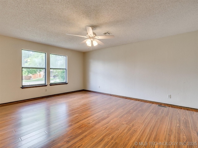 empty room with light wood finished floors, a textured ceiling, visible vents, and ceiling fan