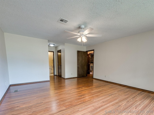 empty room featuring light wood finished floors, visible vents, ceiling fan, and baseboards