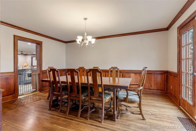 3855 S Utica Ave, Tulsa, OK 74105 - dining space featuring a chandelier, light wood-style floors, wainscoting, and crown molding