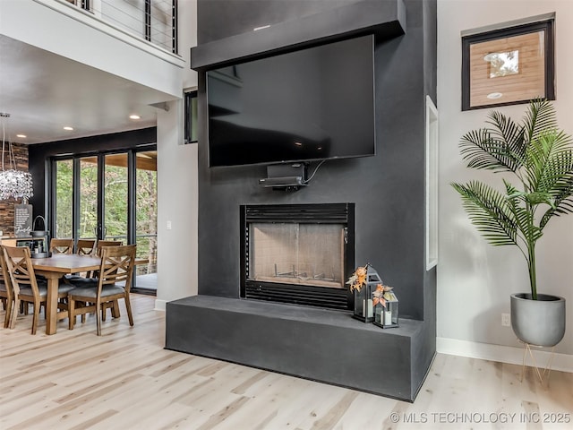 room details featuring baseboards, wood finished floors, a chandelier, and a fireplace with raised hearth