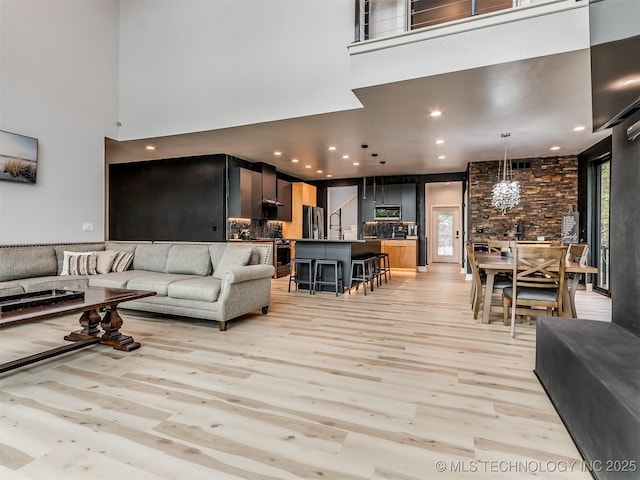living room with a towering ceiling and light wood-style flooring