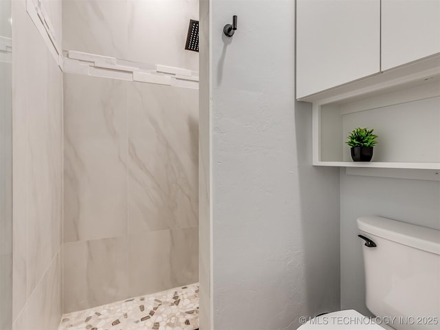 full bath with toilet and tiled shower