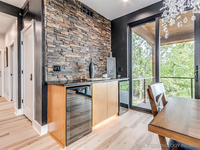 bar with beverage cooler, visible vents, and light wood finished floors