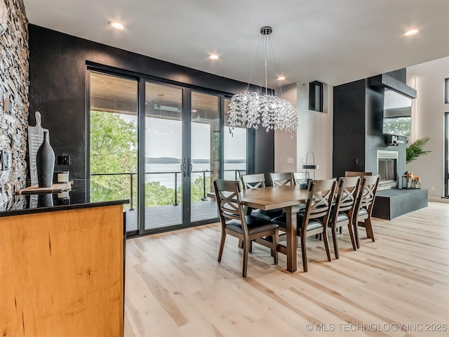 dining space with recessed lighting, a notable chandelier, light wood-style flooring, and a fireplace