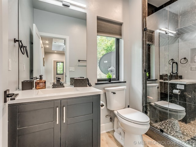 full bath featuring toilet, a shower stall, vanity, and baseboards