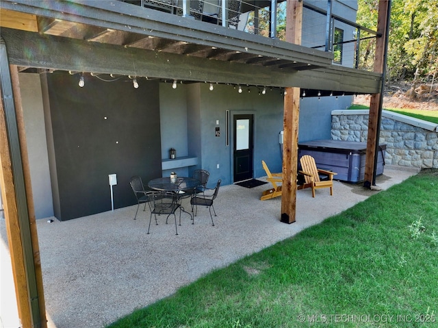 view of patio featuring a balcony and a hot tub