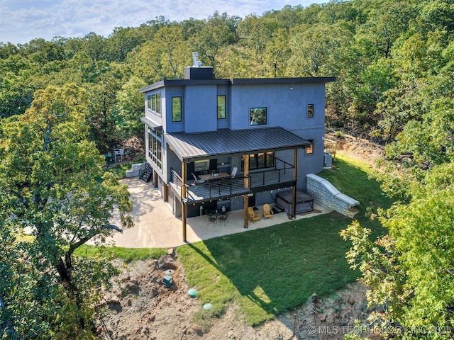 rear view of property featuring stucco siding, a patio area, and a view of trees