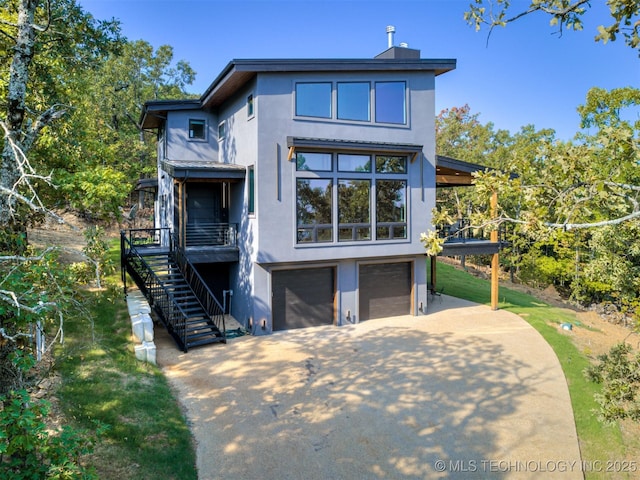 back of house with stucco siding, driveway, stairs, and a garage
