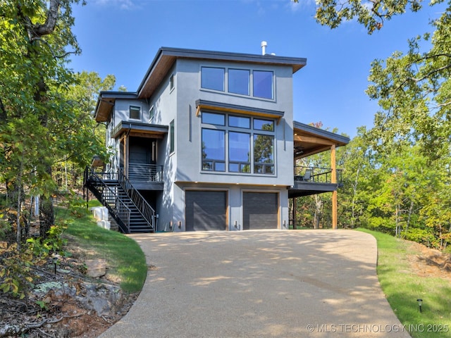 view of front facade with a balcony, stucco siding, stairs, aphalt driveway, and an attached garage