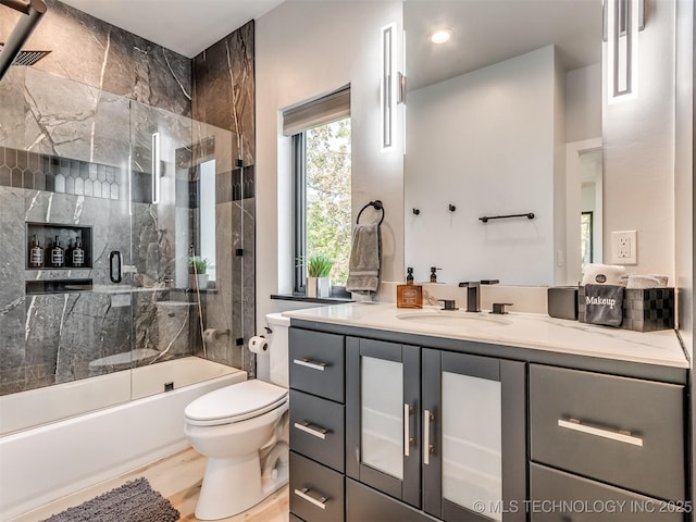 full bathroom with bath / shower combo with glass door, toilet, and vanity