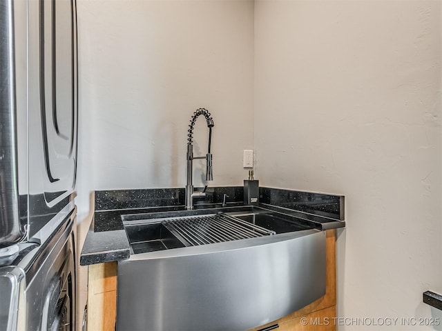 room details featuring stacked washer / dryer and a sink