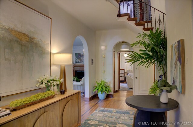 2156 S Owasso Pl, Tulsa, OK 74114 - hallway featuring light wood-style floors, arched walkways, and stairs