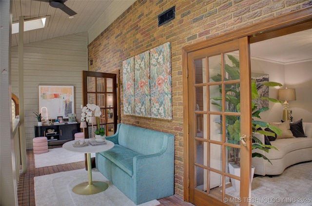 2156 S Owasso Pl, Tulsa, OK 74114 - living area featuring a ceiling fan, brick wall, a skylight, wood finished floors, and high vaulted ceiling