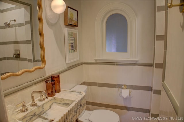 2156 S Owasso Pl, Tulsa, OK 74114 - bathroom with a tile shower, wainscoting, a sink, toilet, and tile walls