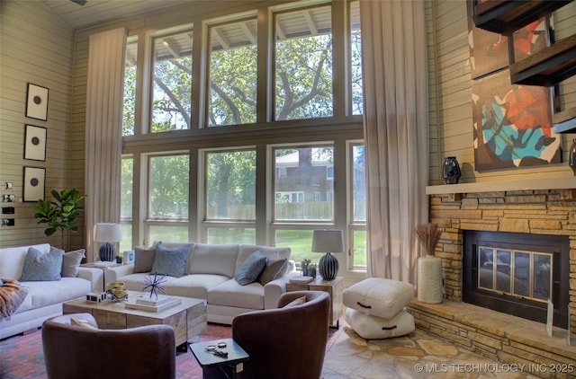 2156 S Owasso Pl, Tulsa, OK 74114 - living area featuring high vaulted ceiling, wood walls, a wealth of natural light, and a fireplace