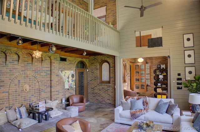 2156 S Owasso Pl, Tulsa, OK 74114 - interior space with wood walls, a towering ceiling, brick wall, ceiling fan, and stone finish flooring