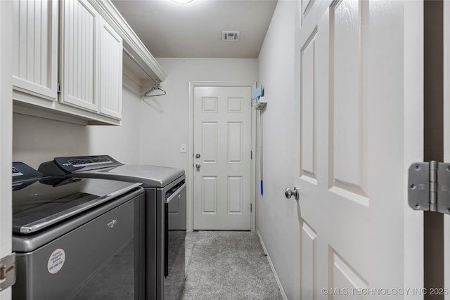 clothes washing area featuring light colored carpet, cabinet space, baseboards, visible vents, and washer and clothes dryer
