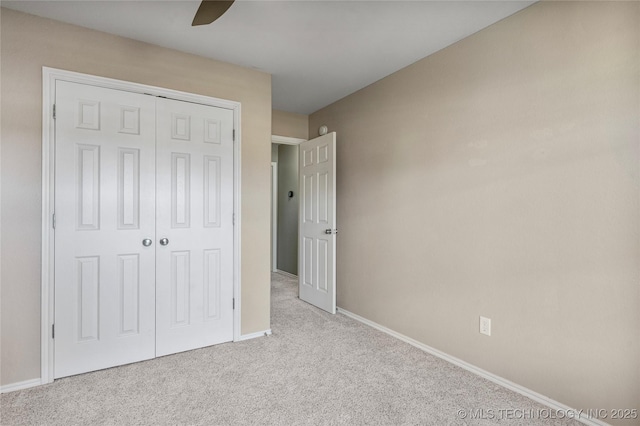 unfurnished bedroom with a closet, a ceiling fan, carpet floors, and baseboards