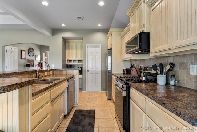 kitchen with appliances with stainless steel finishes, dark countertops, backsplash, a sink, and visible vents