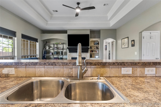 kitchen with a ceiling fan, a sink, open floor plan, and a raised ceiling