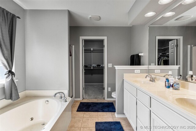 full bath featuring a sink, toilet, double vanity, a tub with jets, and tile patterned flooring