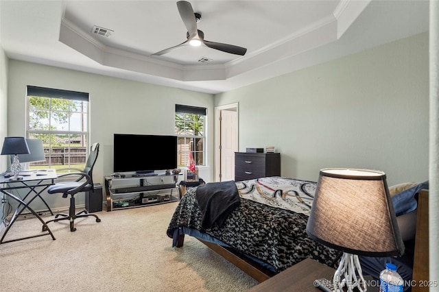 carpeted bedroom with a raised ceiling, multiple windows, and crown molding