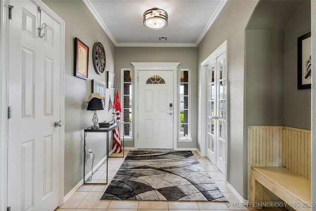 entryway with light tile patterned flooring, crown molding, visible vents, arched walkways, and french doors