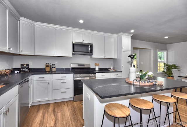 543 N Ridgeway St, Sapulpa, OK 74066 - kitchen with stainless steel appliances, recessed lighting, a kitchen breakfast bar, white cabinetry, and wood finished floors