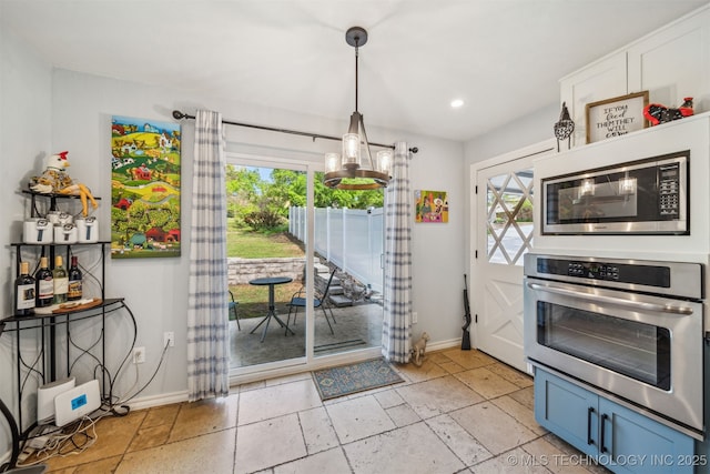 kitchen featuring baseboards, stainless steel appliances, stone tile flooring, and plenty of natural light