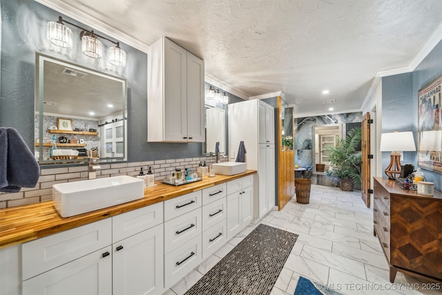 bathroom with visible vents, ornamental molding, marble finish floor, and a sink
