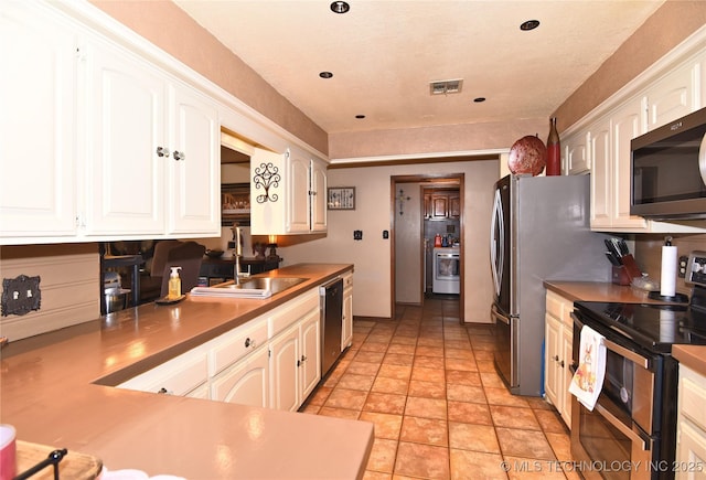 3001 Bacon Rd, Muskogee, OK 74403 - kitchen with stone finish floor, white cabinetry, a sink, stainless steel appliances, and washer / dryer