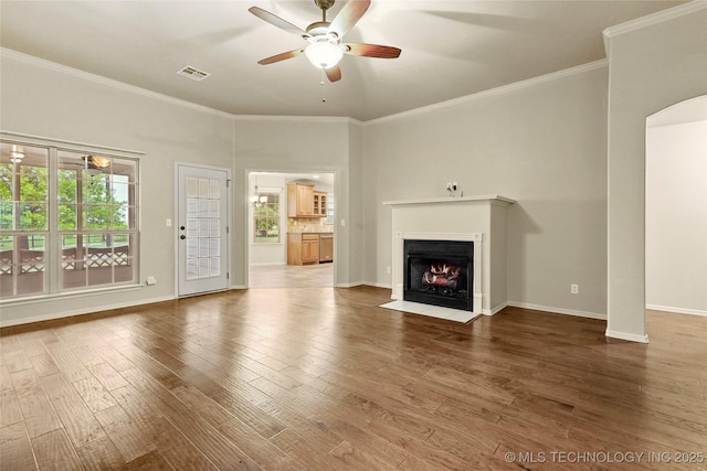 unfurnished living room with visible vents, a ceiling fan, a fireplace with flush hearth, and crown molding