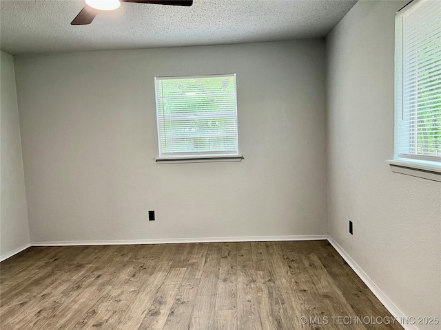 empty room with a ceiling fan, baseboards, wood finished floors, and a textured ceiling
