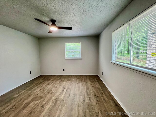 unfurnished room with baseboards, wood finished floors, ceiling fan, and a textured ceiling