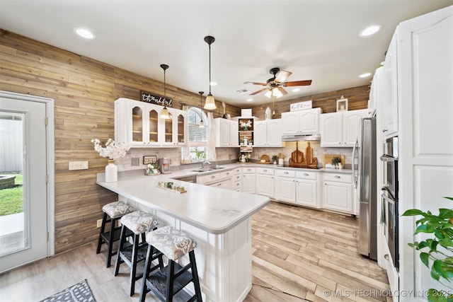 539 N Gunter St, Vinita, OK 74301 - kitchen featuring a kitchen breakfast bar, a sink, freestanding refrigerator, under cabinet range hood, and a peninsula