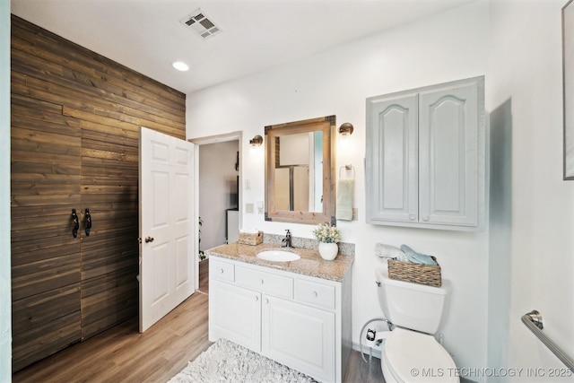 539 N Gunter St, Vinita, OK 74301 - bathroom with vanity, toilet, wooden walls, visible vents, and wood finished floors