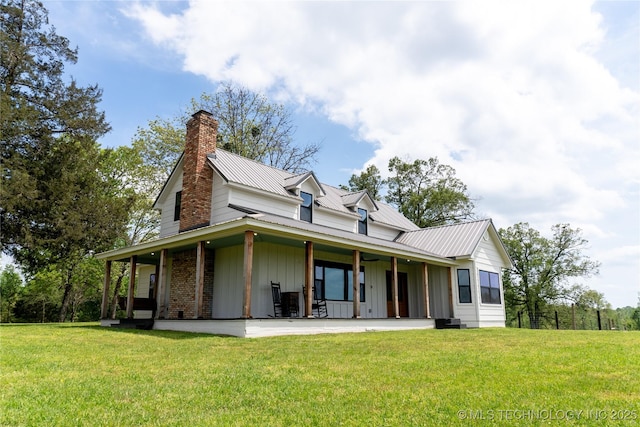 farmhouse inspired home featuring a chimney, board and batten siding, a front lawn, and metal roof
