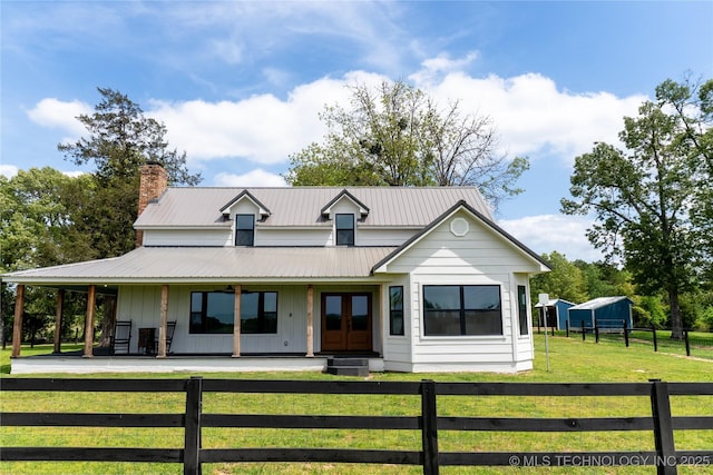 country-style home with a chimney, board and batten siding, a fenced front yard, covered porch, and a front lawn