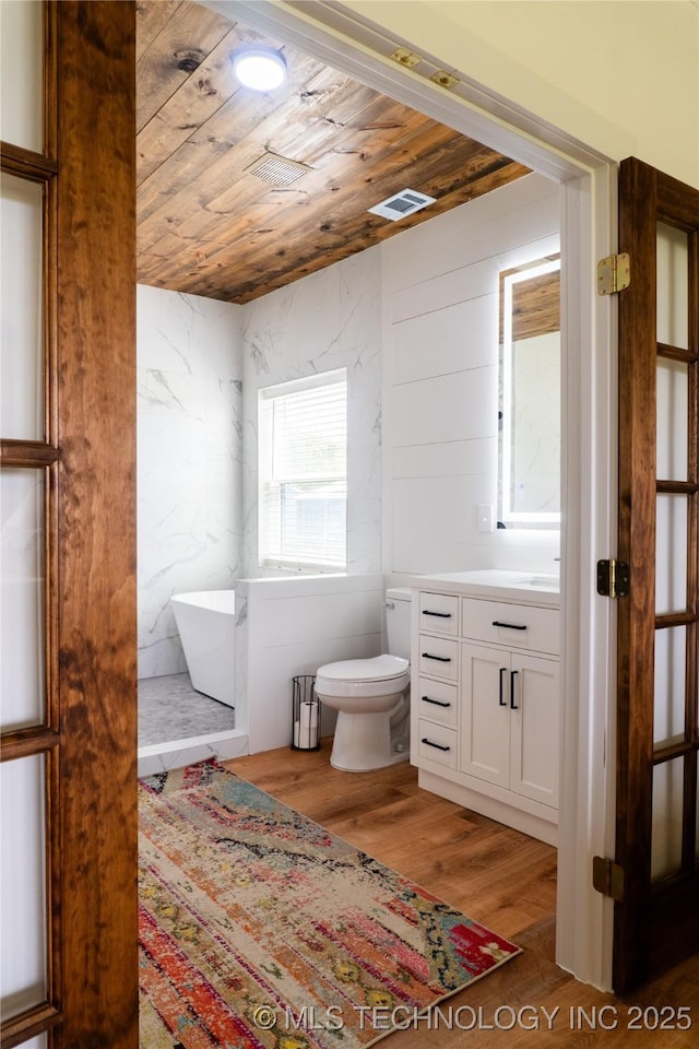 full bath featuring wood ceiling, visible vents, toilet, a freestanding tub, and wood finished floors