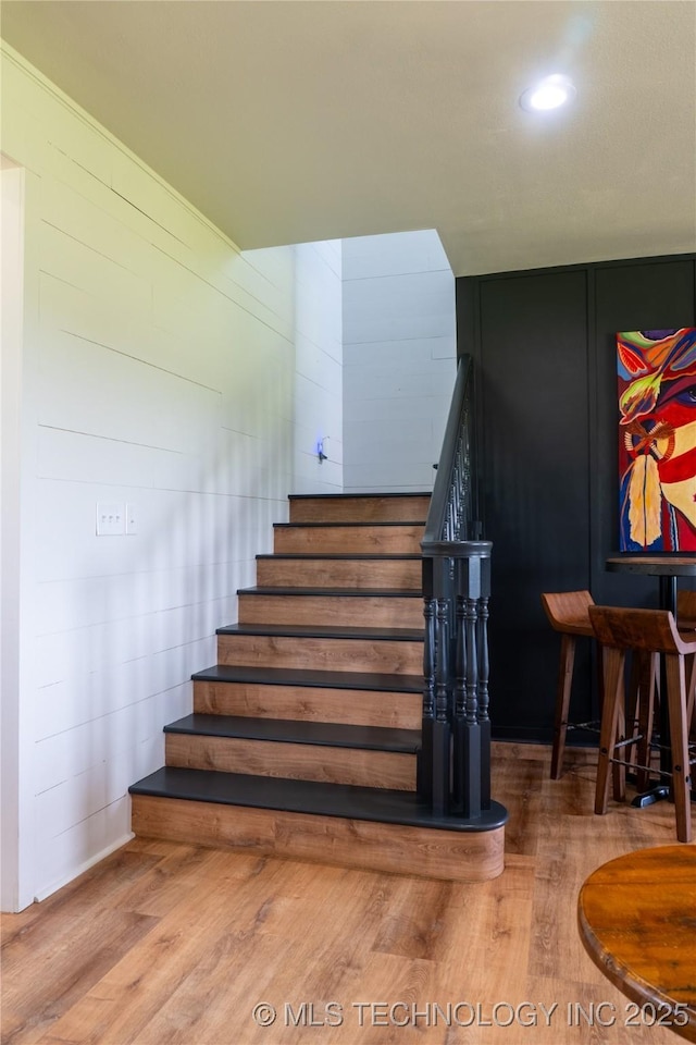 staircase with wood finished floors and recessed lighting