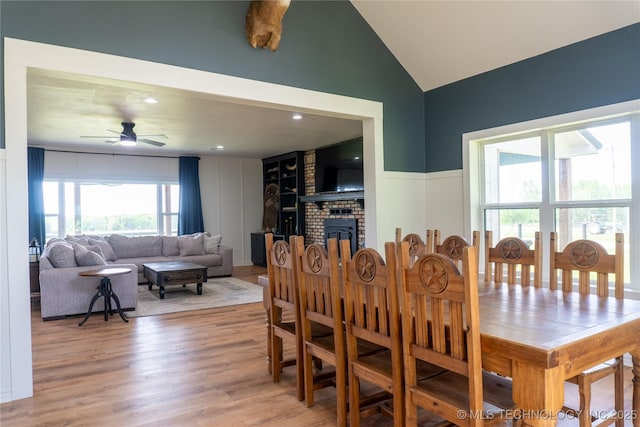 dining room with a fireplace, a ceiling fan, lofted ceiling, and light wood-type flooring