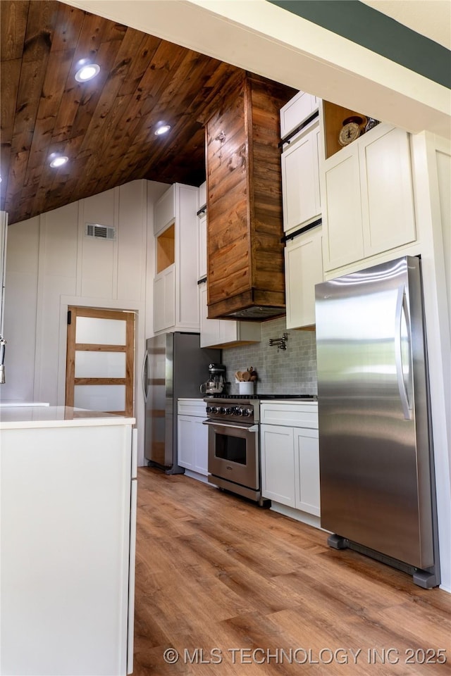 kitchen with light wood-type flooring, tasteful backsplash, visible vents, appliances with stainless steel finishes, and lofted ceiling