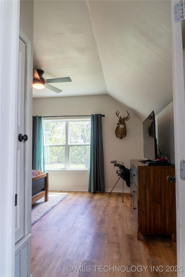 interior space featuring wood finished floors, vaulted ceiling, ceiling fan, baseboards, and visible vents