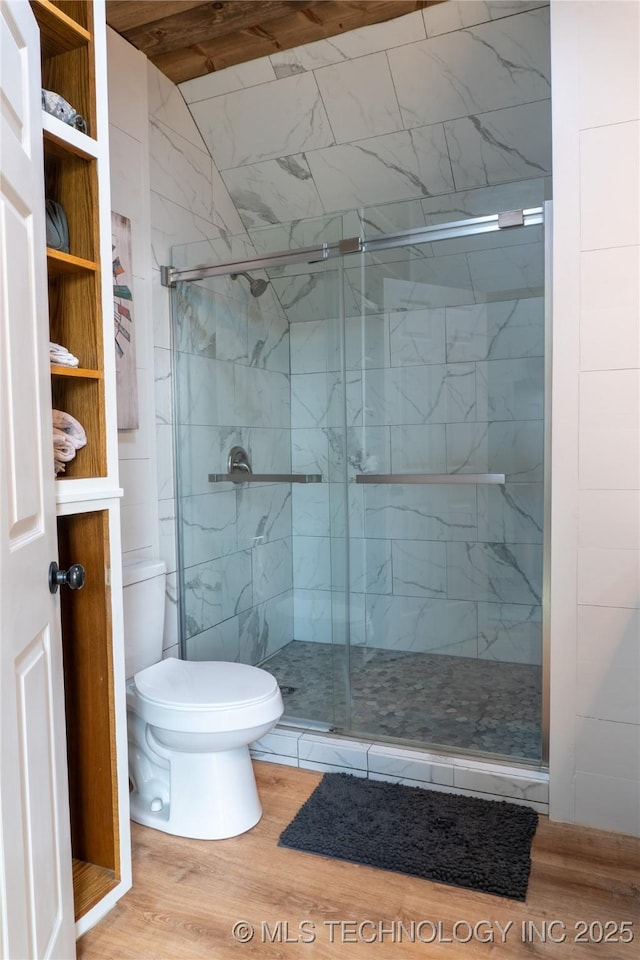 bathroom with wood finished floors, a shower stall, and toilet