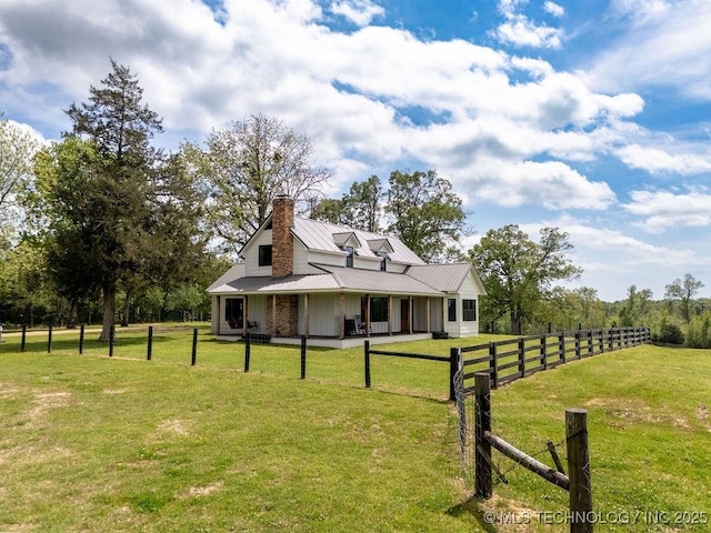 view of side of property with a yard, a chimney, metal roof, and fence