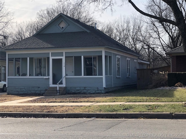 bungalow-style home featuring a porch, a front lawn, and roof with shingles