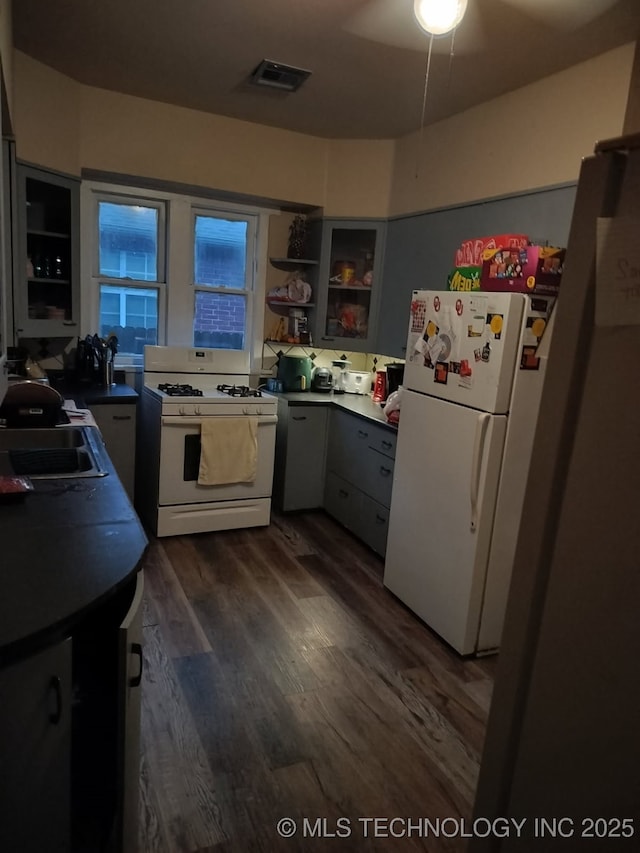 kitchen featuring gray cabinets, white appliances, a sink, visible vents, and dark wood-type flooring