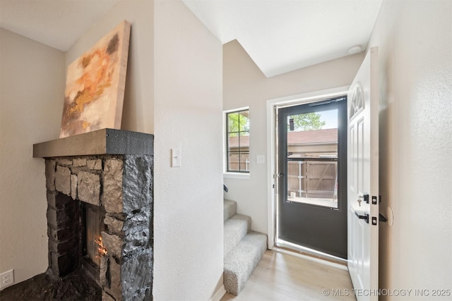 entrance foyer featuring stairway, wood finished floors, a stone fireplace, and baseboards