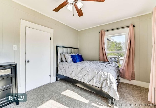carpeted bedroom featuring ornamental molding, ceiling fan, and a decorative wall