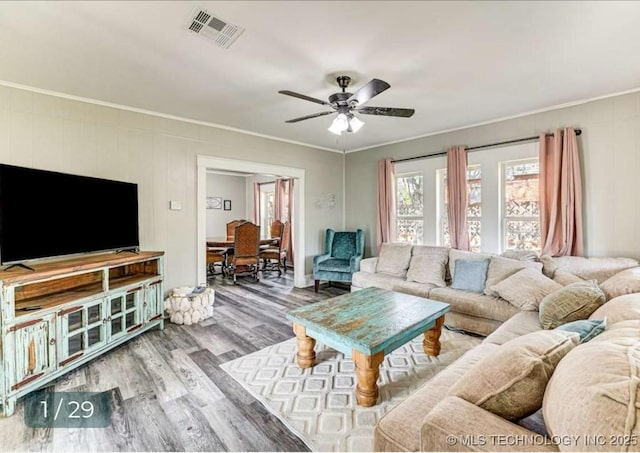 living area featuring wood finished floors, visible vents, a ceiling fan, and crown molding